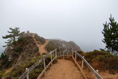 Footpath by railing against sky