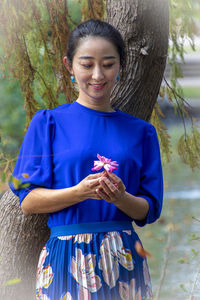 Full length of smiling woman standing against blue sky