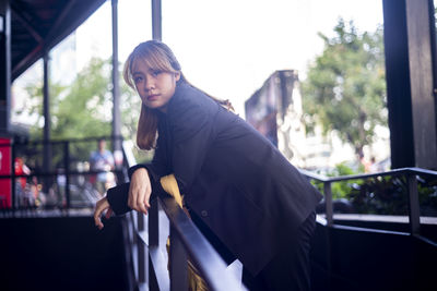 Portrait of businesswoman standing by railing in city