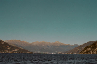 Scenic view of sea and mountains against clear sky