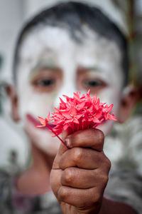 Close-up of hand holding red flower