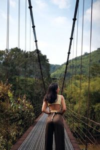 Rear view of woman walking on footbridge