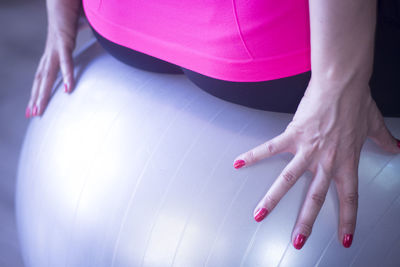 Close-up midsection of woman sitting on fitness ball
