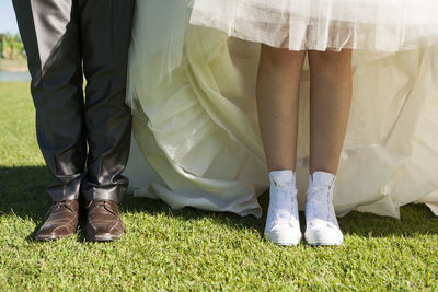 Low section of bride and bridegroom standing on grass