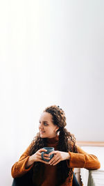 Portrait of young woman sitting against white background