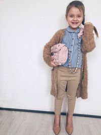 Portrait of smiling girl standing against wall