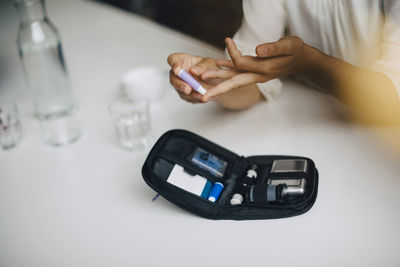 Cropped image of businesswoman doing blood sugar test at table in office