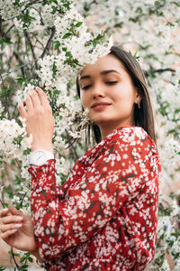 Young woman looking away while standing against plants