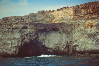 Rock formations by sea against sky