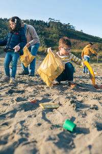 Family picking garbage while cleaning beach