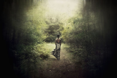 Full length of shirtless man standing in forest