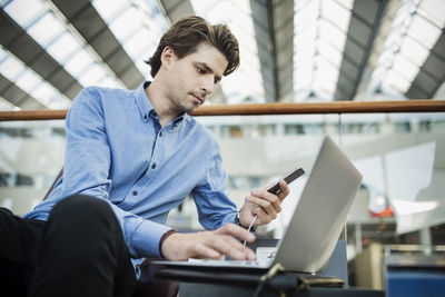 Businessman using laptop and smart phone at airport lobby