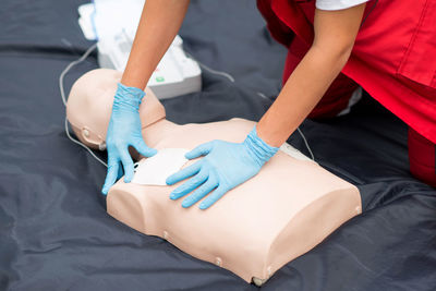 Midsection of paramedic practicing cpr on dummy