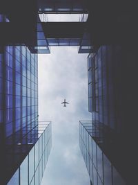 Low angle view of buildings and plane in sky