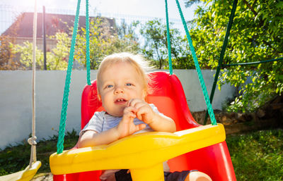 Boy sitting on swing at playground