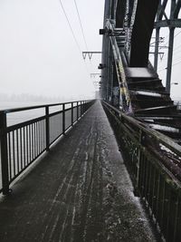 Footbridge by suspension bridge against sky