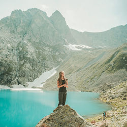 Woman standing on rock by mountains