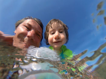 Father with daughter reflecting in water at beach