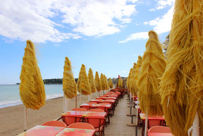 Panoramic view of chairs and table at beach against sky