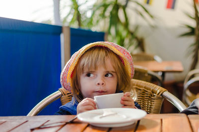 Girl holding coffee cup while sitting in cafe