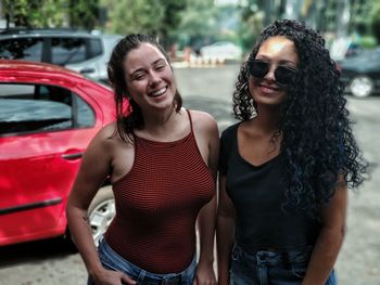 Portrait of cheerful female friends standing on road