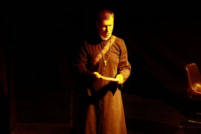 Priest looking away while standing in darkroom