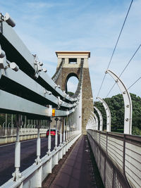 Bridge over railroad tracks against sky