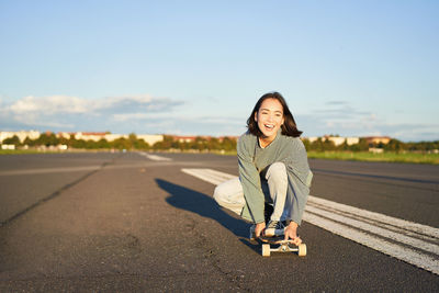 Portrait of young woman standing against sky