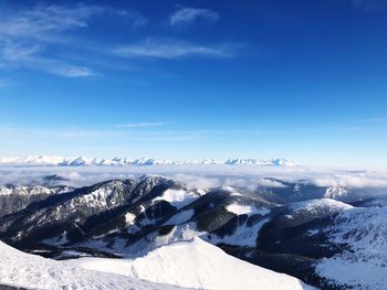 Scenic view of snowcapped mountains against blue sky