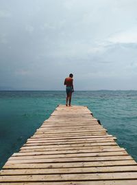 Rear view of man standing on pier