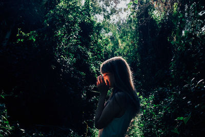 Woman standing by tree trunk