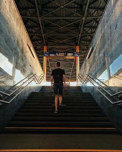 Rear view of man walking on staircase