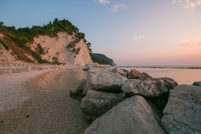 Rocks on beach against sky during sunset