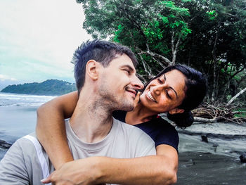 Smiling girlfriend embracing boyfriend at beach