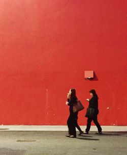 Rear view of people standing against red wall