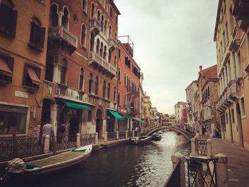 Canal in city against sky