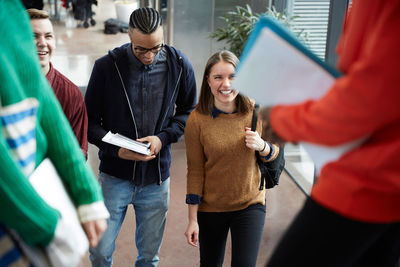 Friends talking to female students standing in university