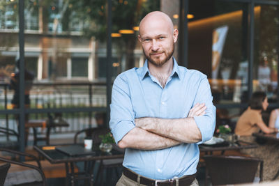 Adult attractive man forty years with beard in blue shirt businessman against glass wall 