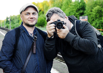 Portrait of man standing with friend photographing with camera