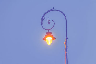 Low angle view of illuminated street light against blue sky