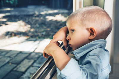 Side view of boy looking through window