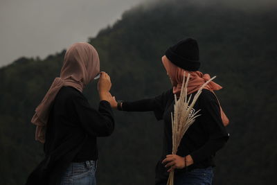 Rear view of friends standing against the mountain