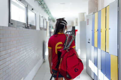 Lacrosse player with backpack walking in locker room