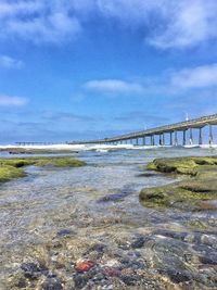 Bridge over sea against cloudy sky