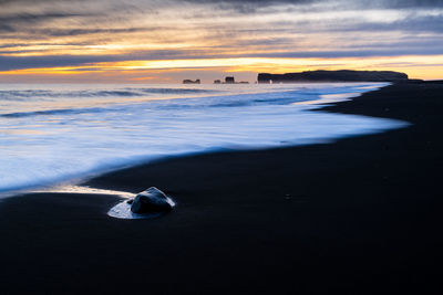 Calm scenic sunset at reynisfjara black sand beach on iceland coast line