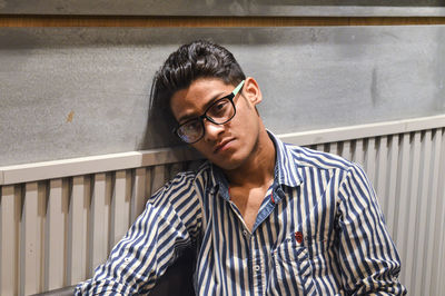 Portrait of young man standing against wall