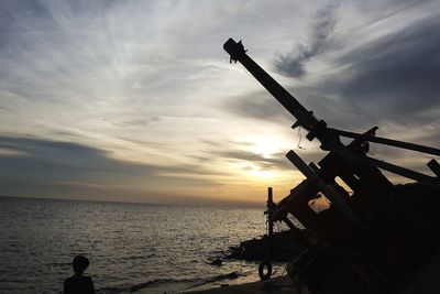 Silhouette man on sea against sky during sunset