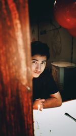 Portrait of boy standing against wall at home