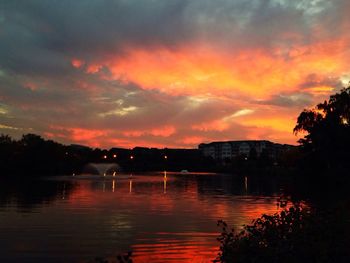 Scenic view of lake against cloudy sky at sunset