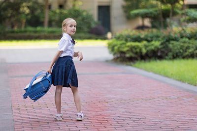 Back to school. little girl with blue backpack from elementary school outdoor